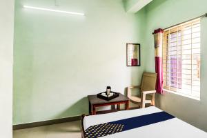 a room with a bed and a table and a window at SPOT ON Gopi Complex in Pīleru