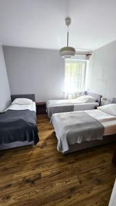 a room with four beds and a large window at Marel- Apartamenty Rydz Polanica Zdrój in Polanica-Zdrój