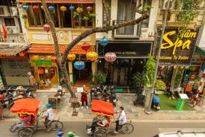 Eine Gruppe von Menschen, die auf Fahrrädern eine Stadtstraße hinunterfahren in der Unterkunft Golden Time Hostel 3 in Hanoi