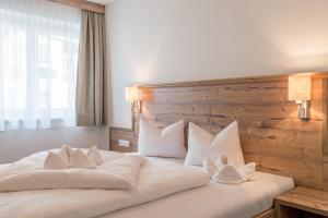 1 dormitorio con 1 cama blanca grande con almohadas blancas en A Casa Saphir Appartement-Hotel, en Sölden