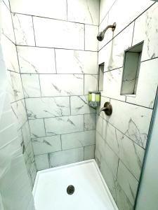 y baño con ducha y azulejos de mármol blanco. en Modern Cozy walk up with King Bed, en Wilmington
