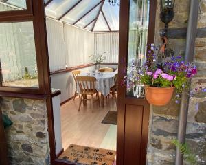 a conservatory with a table and flowers in a pot at Old Stable Cottage Nanternis in Llanllwchaiarn