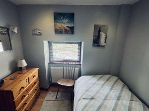 ein Schlafzimmer mit einem Bett, einer Kommode und einem Fenster in der Unterkunft Old Stable Cottage Nanternis in Llanllwchaiarn