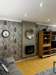 a living room with a fireplace and a clock on the wall at Spacious 4-Bed Haven - Free Parking & Wi-Fi in Whitefield
