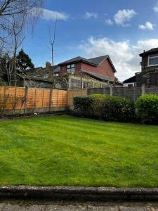 a yard with a fence and a house at Spacious 4-Bed Haven - Free Parking & Wi-Fi in Whitefield