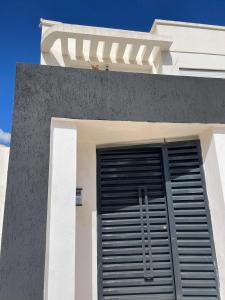 a white building with a black garage door on it at Appartement Bonaventure Yasmine Hammamet in Hammamet