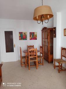 uma sala de jantar com uma mesa e cadeiras e um lustre em apartamento em Conil de la Frontera