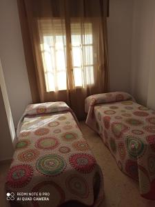 Duas camas num quarto com uma janela em apartamento em Conil de la Frontera