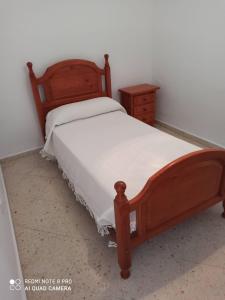 um quarto com uma cama de madeira e uma mesa de cabeceira em apartamento em Conil de la Frontera