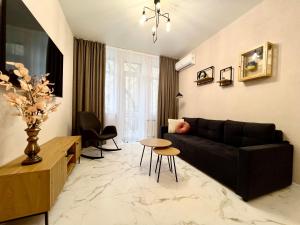 a living room with a black couch and a table at ЛЮКС на Собрной с 2-мя спальнями, Спасская50 in Mykolaiv