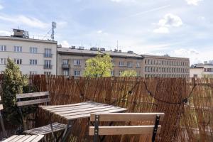 a wooden table and benches in front of a fence at Kraków Apartments - Balcony, Workspace, Tram stop - by Rentujemy in Krakow
