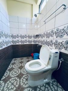 a bathroom with a toilet and a tiled wall at Rivera Holiday Home in Vythiri