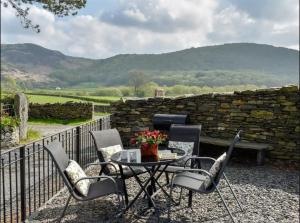 a patio with a table and chairs and a stone wall at Pass the Keys Cosy 2 bedroom cottage near Coniston water in Ulverston