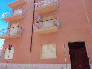 an orange building with balconies and a door at Casa vacanze ferro in Trapani
