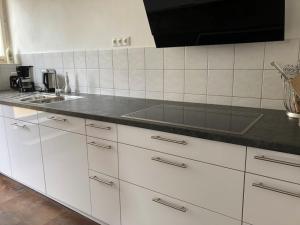 a kitchen with white cabinets and a black counter top at Villa Steigerwald in Oberscheinfeld
