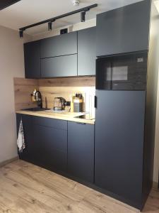 a kitchen with black cabinets and a refrigerator at Zaruskiego 2 in Ustka