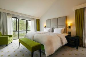 a bedroom with a large bed and a green chair at Kempinski Hotel Frankfurt Gravenbruch in Gravenbruch