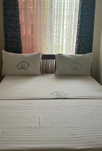 un letto con due cuscini e una finestra di G & S Executive Lodge a Dar es Salaam