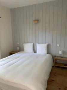 een slaapkamer met een groot wit bed met twee kussens bij Villa DUNE in Biscarrosse +21 foto's