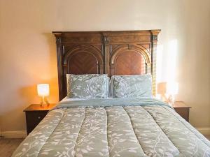 a large bed with a wooden headboard and two lamps at Luxurious 4br 3 baths office game room - 85 inch TV - Close to fishing boating and outdoors activities in Wylie