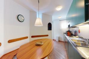 a kitchen with a wooden table and a clock on the wall at Apartment Cristolais in Samedan