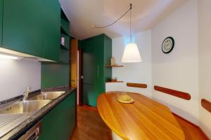 a kitchen with green cabinets and a wooden table at Apartment Cristolais in Samedan