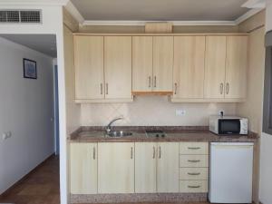 una cucina con armadi in legno, lavandino e forno a microonde di Villas Montemar a San José