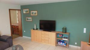 a living room with a flat screen tv on a cabinet at Ferienwohnung Eifelrose in Vorpochten