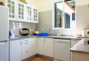 a white kitchen with white cabinets and a window at GuestReady - Hikers Haven in Faial