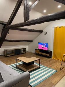 a living room with a couch and a tv at Les Loges de la Commanderie ! in Coulommiers