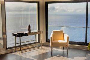 una silla y una mesa en una habitación con ventanas en Zula House - Stunning designer villa in spectacular location, en Caniço