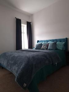 - une chambre avec un lit doté d'une couverture bleue et d'une fenêtre dans l'établissement Gorgeous Edwardian Terrace in Old Trafford, à Manchester
