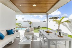 an outdoor patio with white furniture and a wooden ceiling at Casa Beyel La Concha in Playa Honda