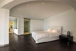 een slaapkamer met een wit bed en een zwarte tegelvloer bij Zula House - Stunning designer villa in spectacular location in Caniço
