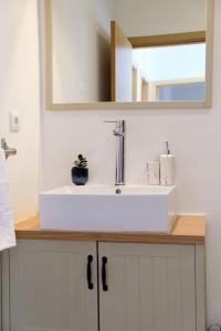 een witte wastafel in een badkamer met een spiegel bij GuestReady - Charming Caniço Retreat in Caniço