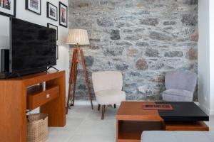 uma sala de estar com televisão e uma parede de pedra em GuestReady - Quiet house & heated pool w sea view em Prazeres