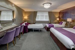 a hotel room with two beds and a table and chairs at Burnley West Higher Trapp Hotel in Padiham