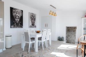 uma sala de jantar branca com uma mesa e cadeiras brancas em GuestReady - Quiet house & heated pool w sea view em Prazeres