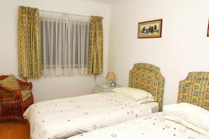 a bedroom with two beds and a chair at Formosa Sunset - Em frente à praia com wifi in Funchal