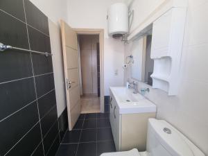 a white bathroom with a sink and a toilet at Lea Apartament in Sarandë