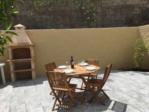 a wooden table with chairs and a bottle of wine at Windmill House- Near beach in Porto Santo