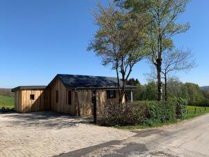 eine Holzscheune mit einem Baum neben einer Straße in der Unterkunft Ferienhaus mit Privatpool für 4 Personen ca 120 m in Trois-Ponts, Wallonie Spa-Francorchamps und Umgebung in Trois-Ponts
