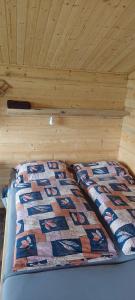 a bed in a wooden room with a quilt on it at Chata na samotě, Šumava in Vrhaveč