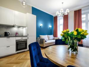cocina y sala de estar con mesa de madera con flores en Tyzenhauz Suites Topolowa, en Cracovia