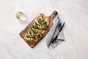 a pizza sitting on top of a wooden cutting board at EVEN Hotel Austin Uptown near the Domain, an IHG Hotel in Austin
