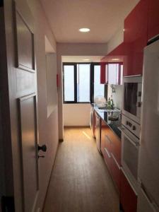 a kitchen with red cabinets and a hallway with a door at Cliff View III - Sea View + Pool + Wifi in Ilhéu do Gorgulho