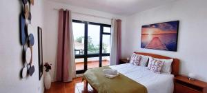 a bedroom with a bed and a large window at Madeira - Sunset Sea View of Cabo Girão in Panasqueira