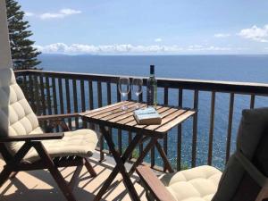 a table with two chairs and a bottle of wine on a balcony at Cliff View III - Sea View + Pool + Wifi in Ilhéu do Gorgulho +29 photos