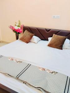 Una cama blanca con almohadas y flores. en Grand Hotel Inn, en Gaya