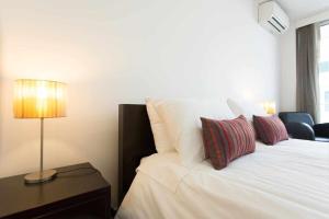 a bedroom with a white bed with pillows and a lamp at Dolce Vita - City Center & Shopping Center in Funchal